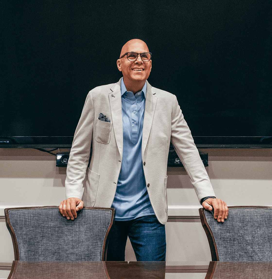 Professional portrait of Chris Flakus, CEO of CSI Companies, smiling and standing in a boardroom, representing executive leadership and vision in workforce solutions.